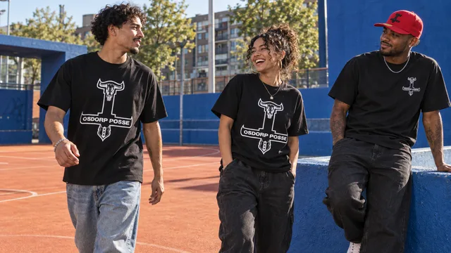 Drie modellen dragen zwarte T-shirts met bedrukking